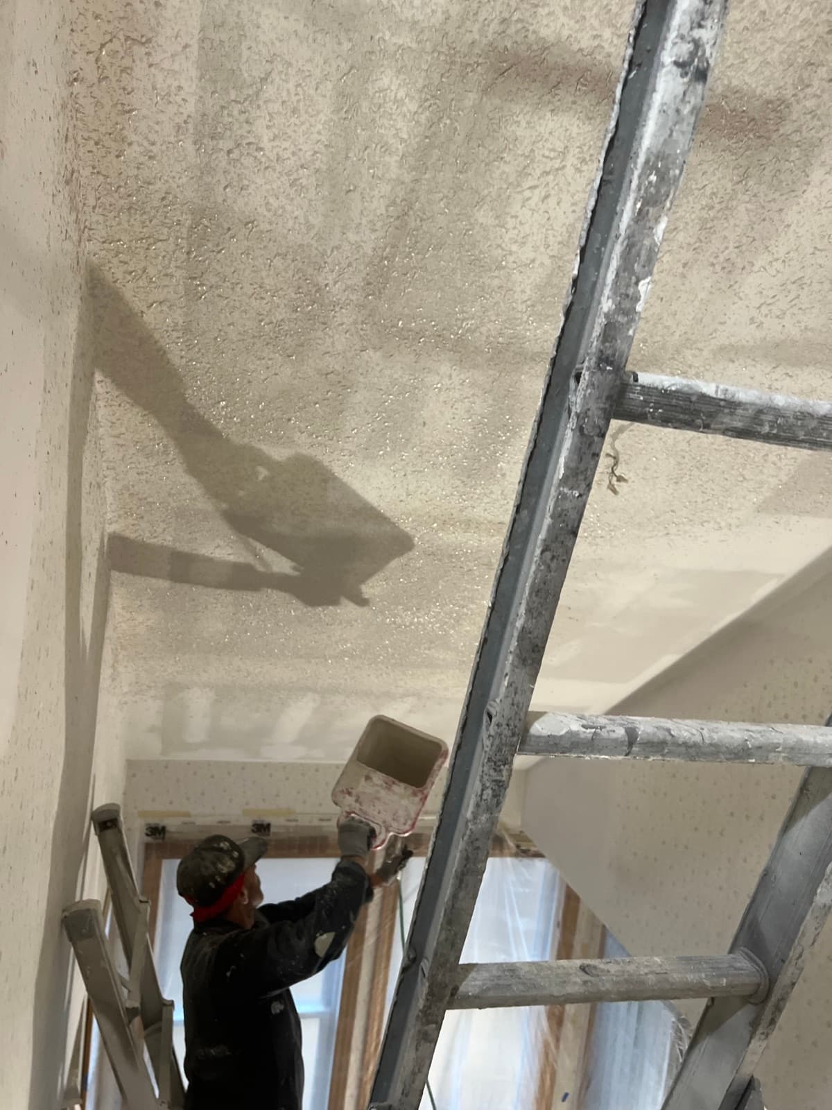 Ruiz Painting crew applying ceiling texture from a ladder